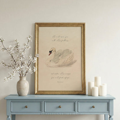 a framed print of a swan on a blue table, accompanied by a vase of white flowers and three white candles.