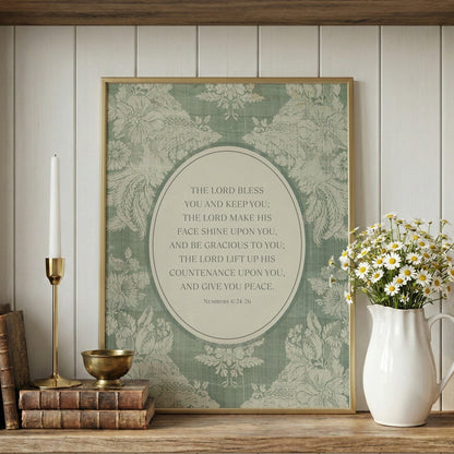 a framed print with a religious text, a white vase with white flowers, a stack of books, and a brass candlestick on a wooden shelf.