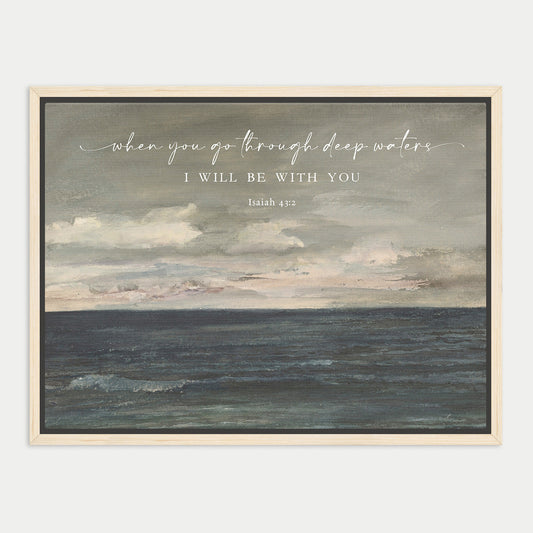 The image is a framed painting depicting a serene ocean scene with a cloudy sky above. The text overlay reads "when you go through deep waters, I will be with you" and is attributed to Isaiah 43:13.
