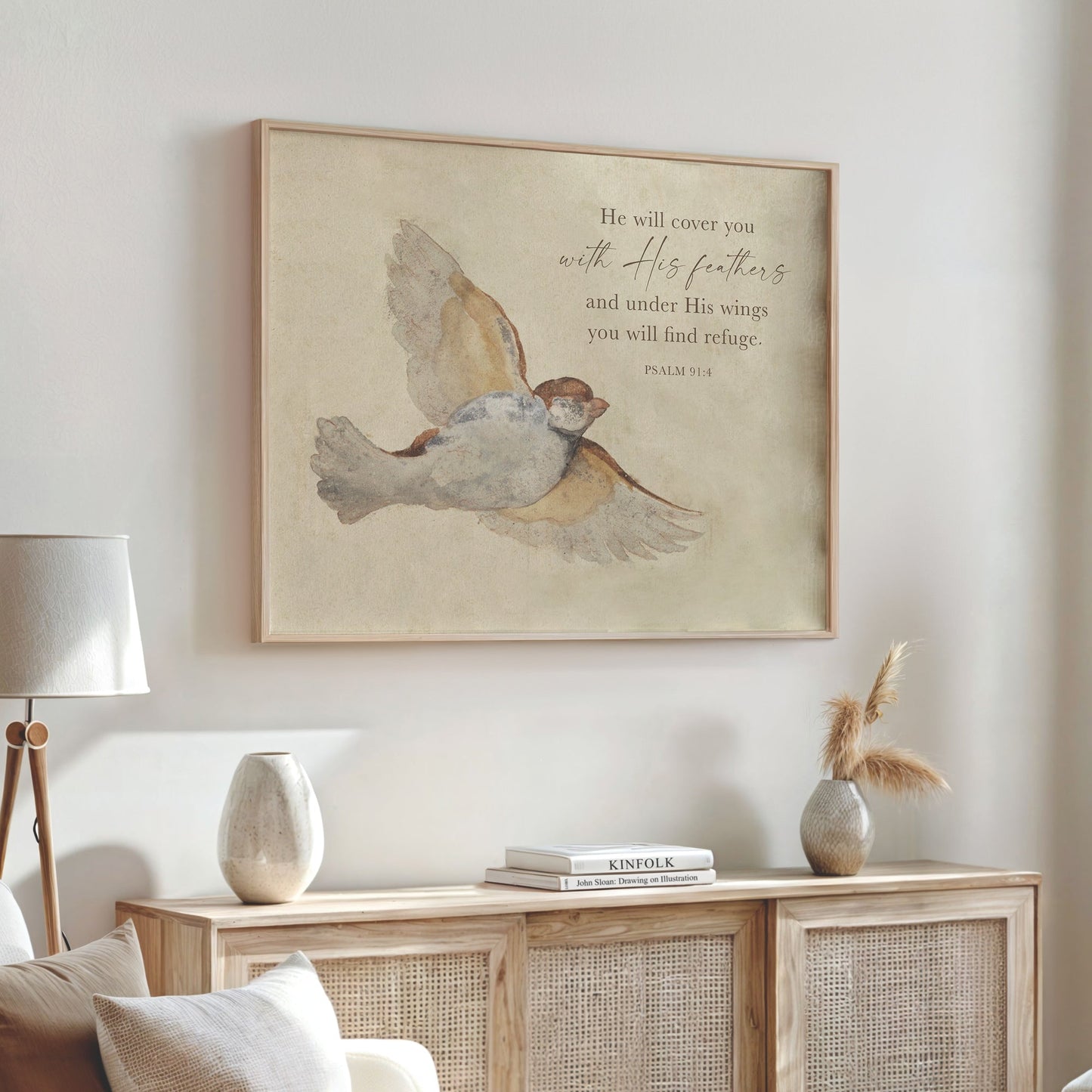 a framed painting of a bird in flight, hanging on a wall above a wooden cabinet or dresser. The painting is accompanied by a Bible verse from Psalm 19:1, which reads "He will cover you with His feathers and under His wings you will find refuge."