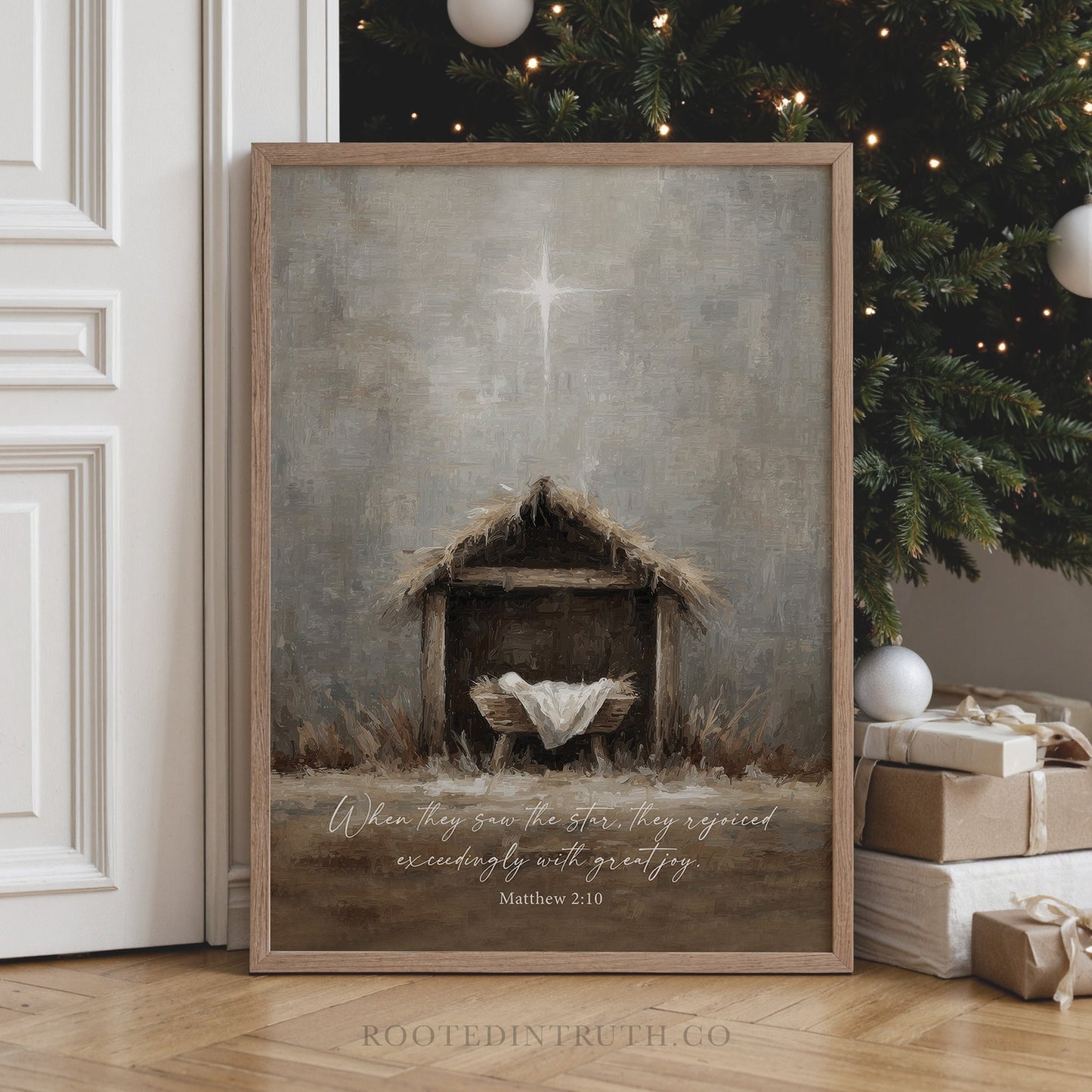 a framed painting of a nativity scene with a wooden manger and a baby in a manger, set against a backdrop of a Christmas tree and presents.