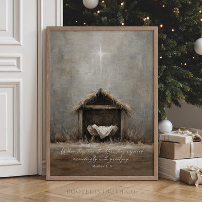 a framed painting of a nativity scene with a wooden manger and a baby in a manger, set against a backdrop of a Christmas tree and presents.