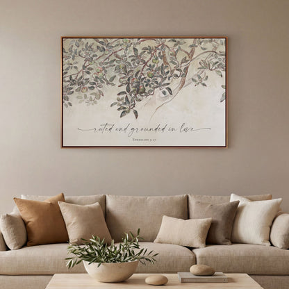 a living room with a beige sofa adorned with throw pillows, a coffee table with a plant, and a framed print of a tree with green leaves hanging above the sofa.