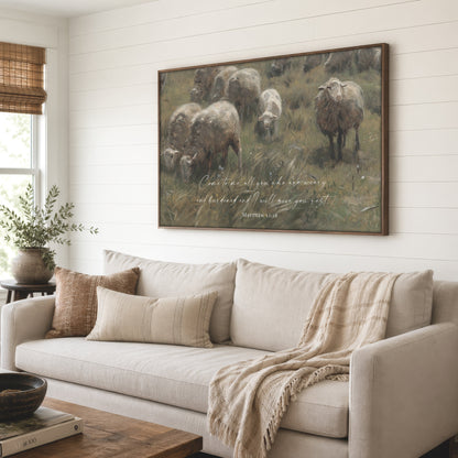 a large painting of a pastoral scene with sheep grazing in a grassy field, hanging on a wall above a beige sofa in a cozy living room setting.