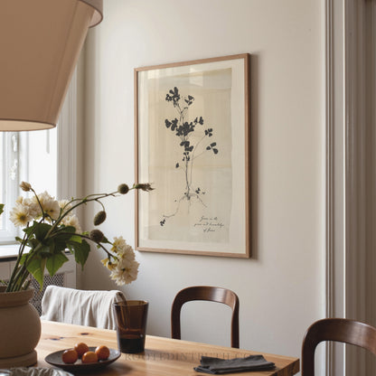 a dining room with a wooden table, two chairs, a vase with flowers, and a framed print hanging on the wall.