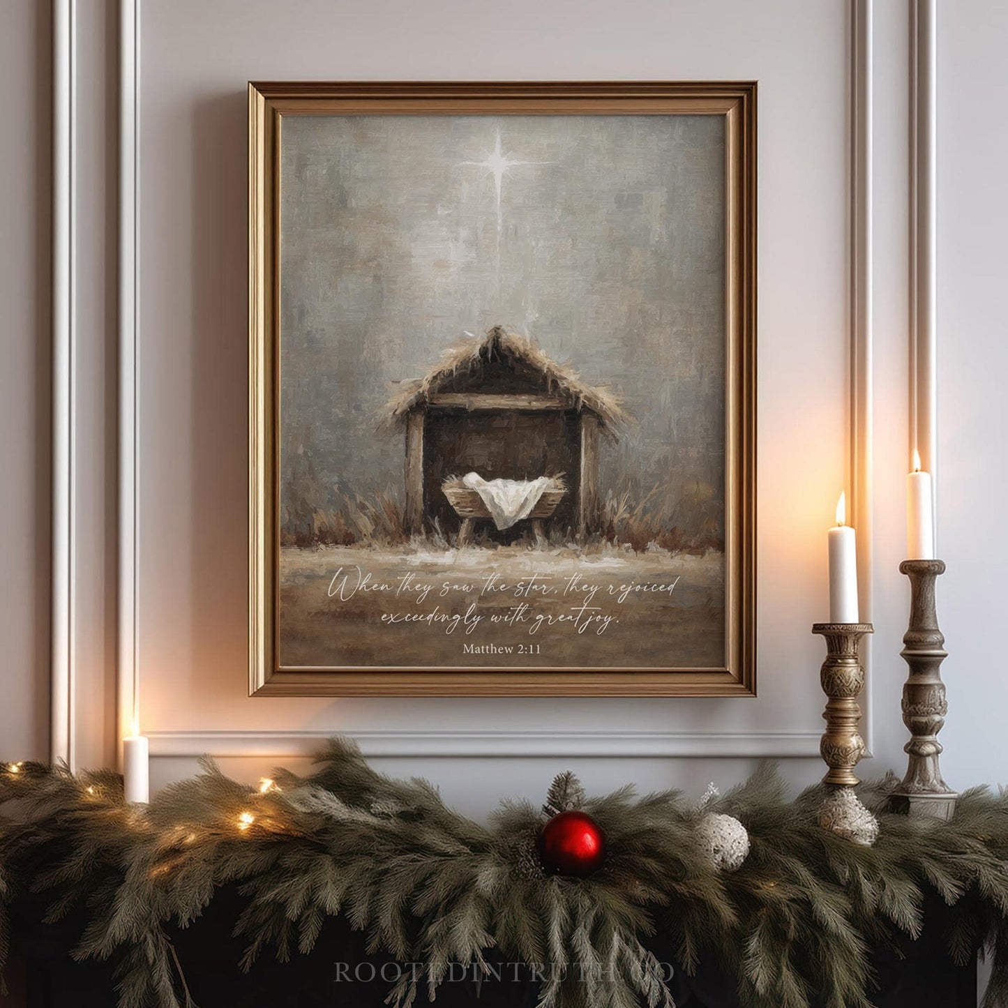 a framed painting of a nativity scene with a wooden stable and a baby in a manger, surrounded by greenery and lit candles.