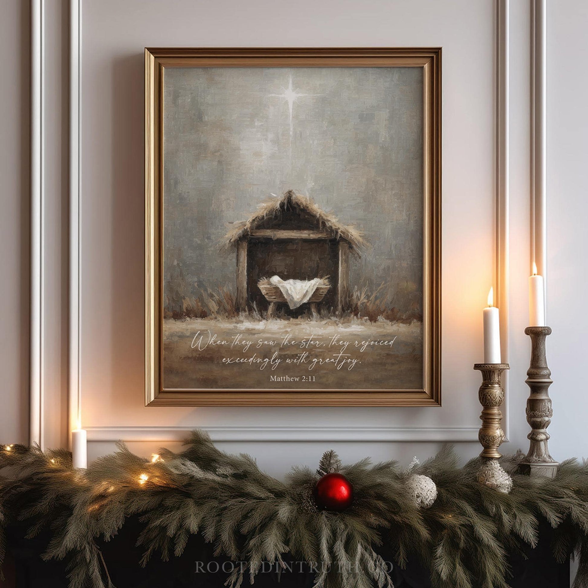 a framed painting of a nativity scene with a wooden stable and a baby in a manger, surrounded by greenery and lit candles.