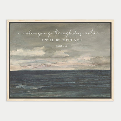 The image is a framed painting depicting a serene ocean scene with a cloudy sky above. The text overlay reads "when you go through deep waters, I will be with you" and is attributed to Isaiah 43:13.
