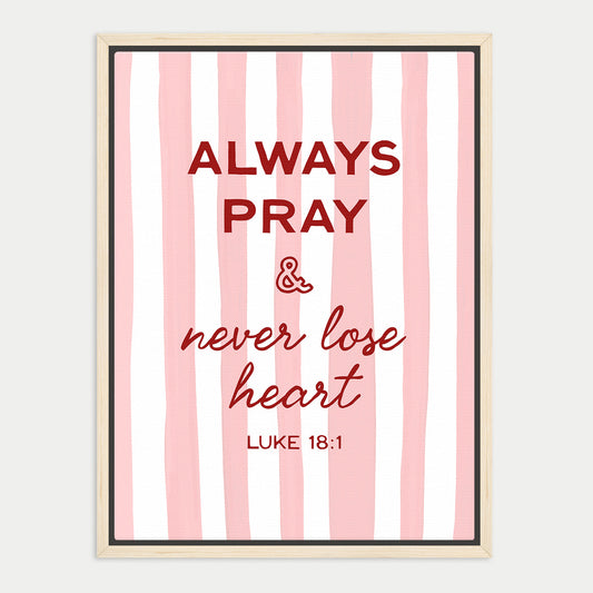 a framed poster with a pink and white striped background. The poster contains a religious quote from the Bible, specifically Luke 18:1, which reads "Always Pray & never lose heart".