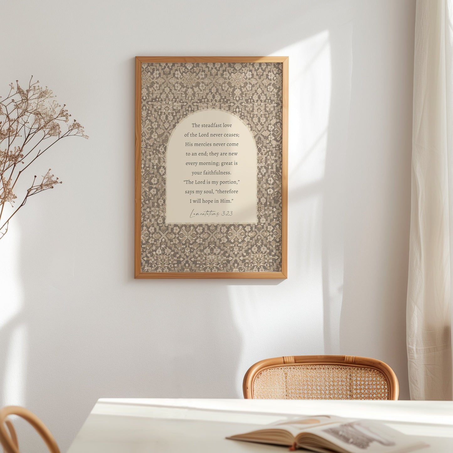 a framed quote with a floral pattern on the wall, accompanied by a wooden chair and a book on a table.