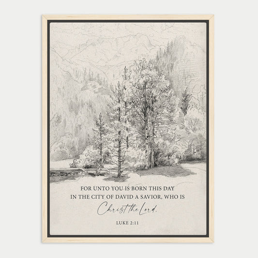 The image is a framed print featuring a black and white illustration of a forest landscape with mountains in the background. The text below the image reads, "FOR UNTO YOU IS BORN THIS DAY IN THE CITY OF DAVID A SAVIOR, WHO IS CHRIST THE LORD. LUE 211".