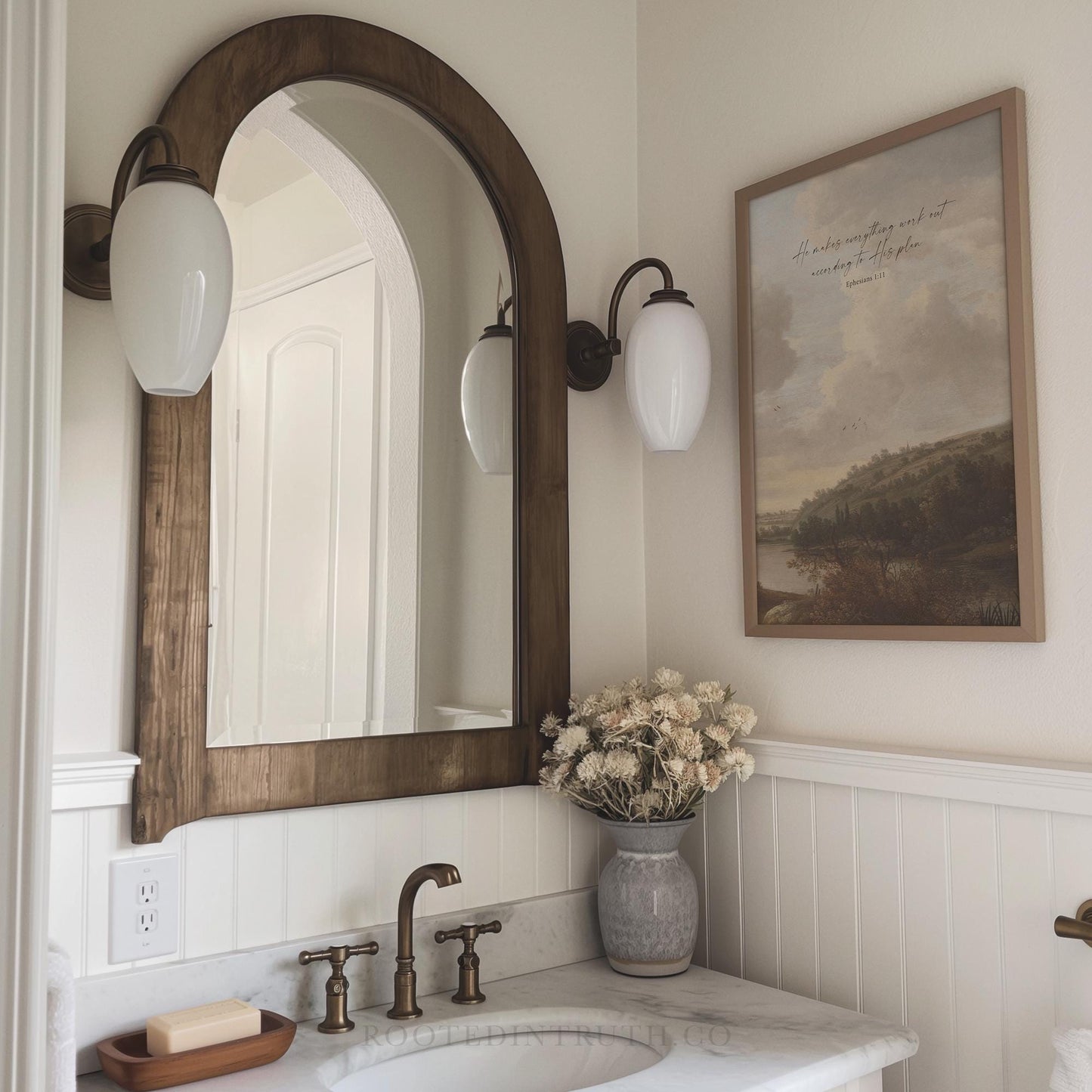 A Christian vintage wall art print with a scripture bible verse. Moody landscape in a bathroom with a sink and a mirror.