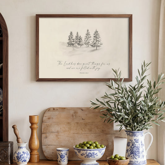 a wooden shelf with various decorative items, including a framed print of a winter landscape, a vase of green leaves, a bowl of fruit, and a wooden tray.