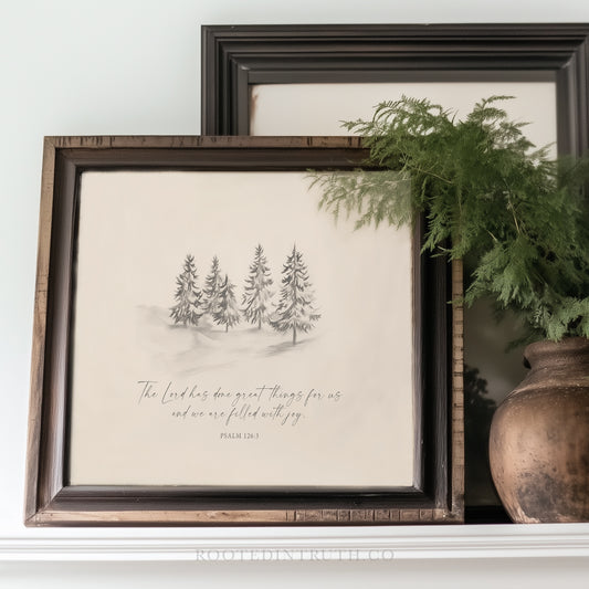 a framed print of a winter landscape with pine trees, accompanied by a Bible verse from Psalm 13:3. The print is placed on a shelf next to a vase with greenery.