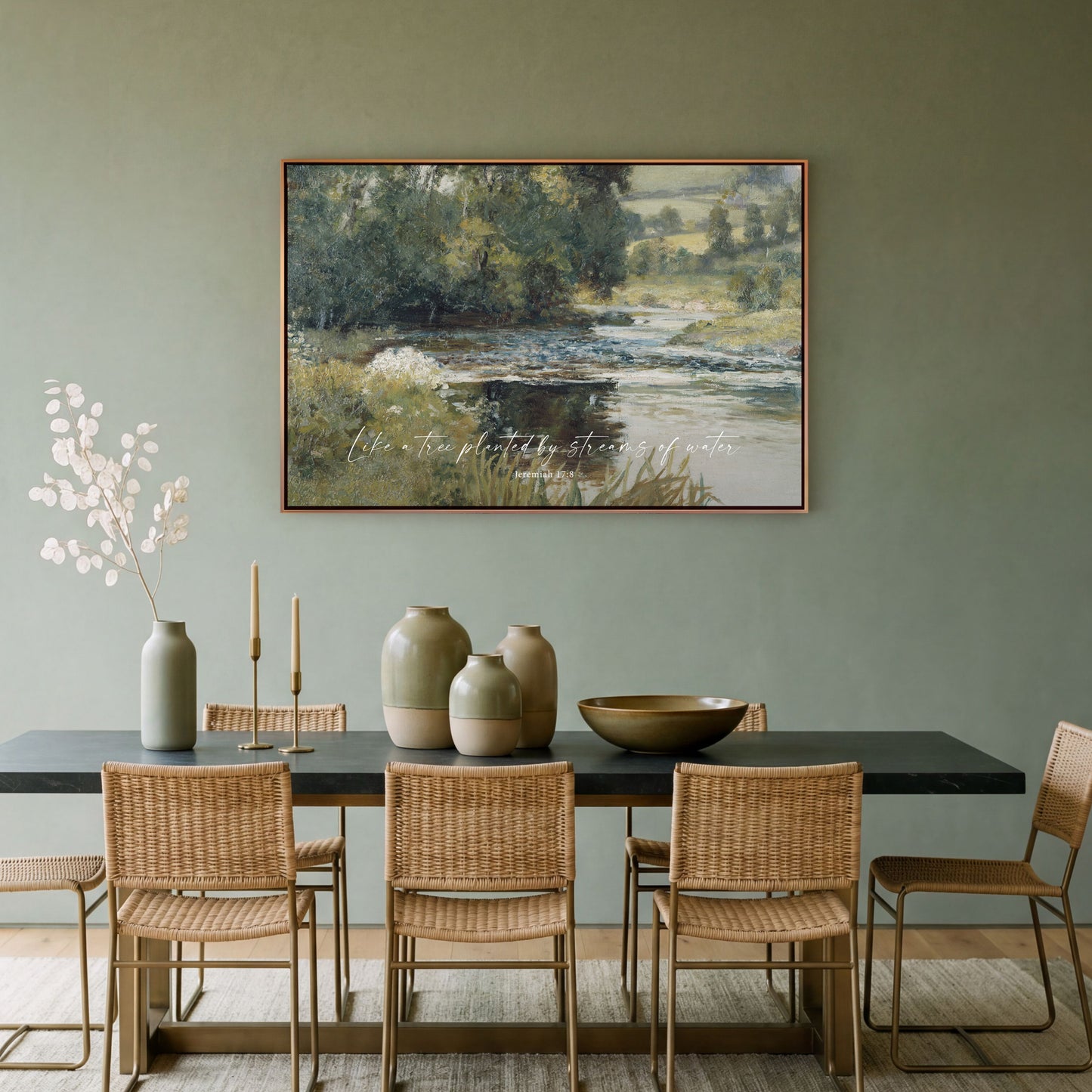 a dining room with a large painting of a serene landscape hanging on the wall above a table with wicker chairs. The table is set with various decorative items, including vases and a bowl.