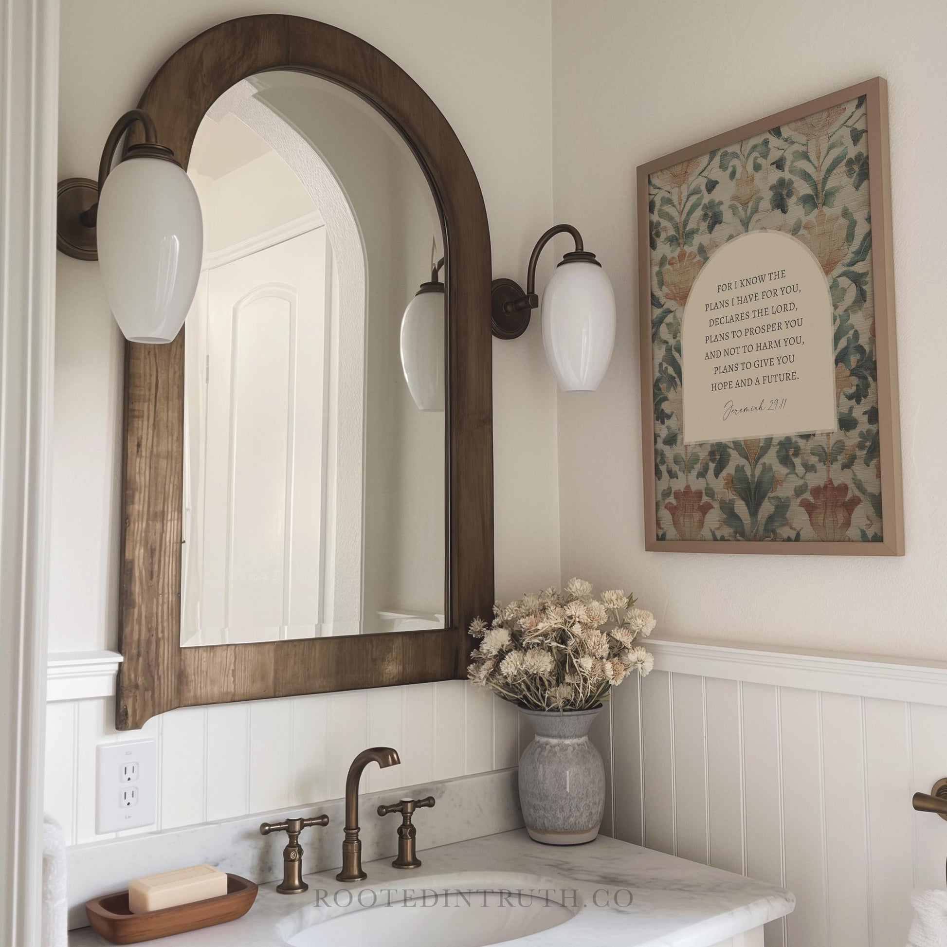 a bathroom with a white sink, a wooden framed mirror, and a framed inspirational quote on the wall.