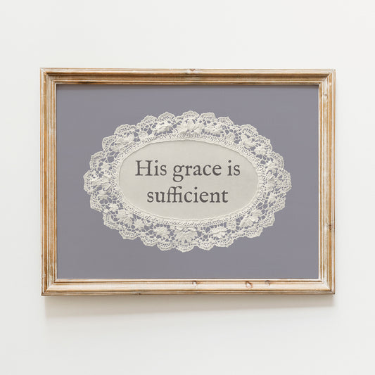 a framed piece of art with a lace doily in the center, surrounded by a wooden frame. The text on the doily reads "His grace is sufficient".
