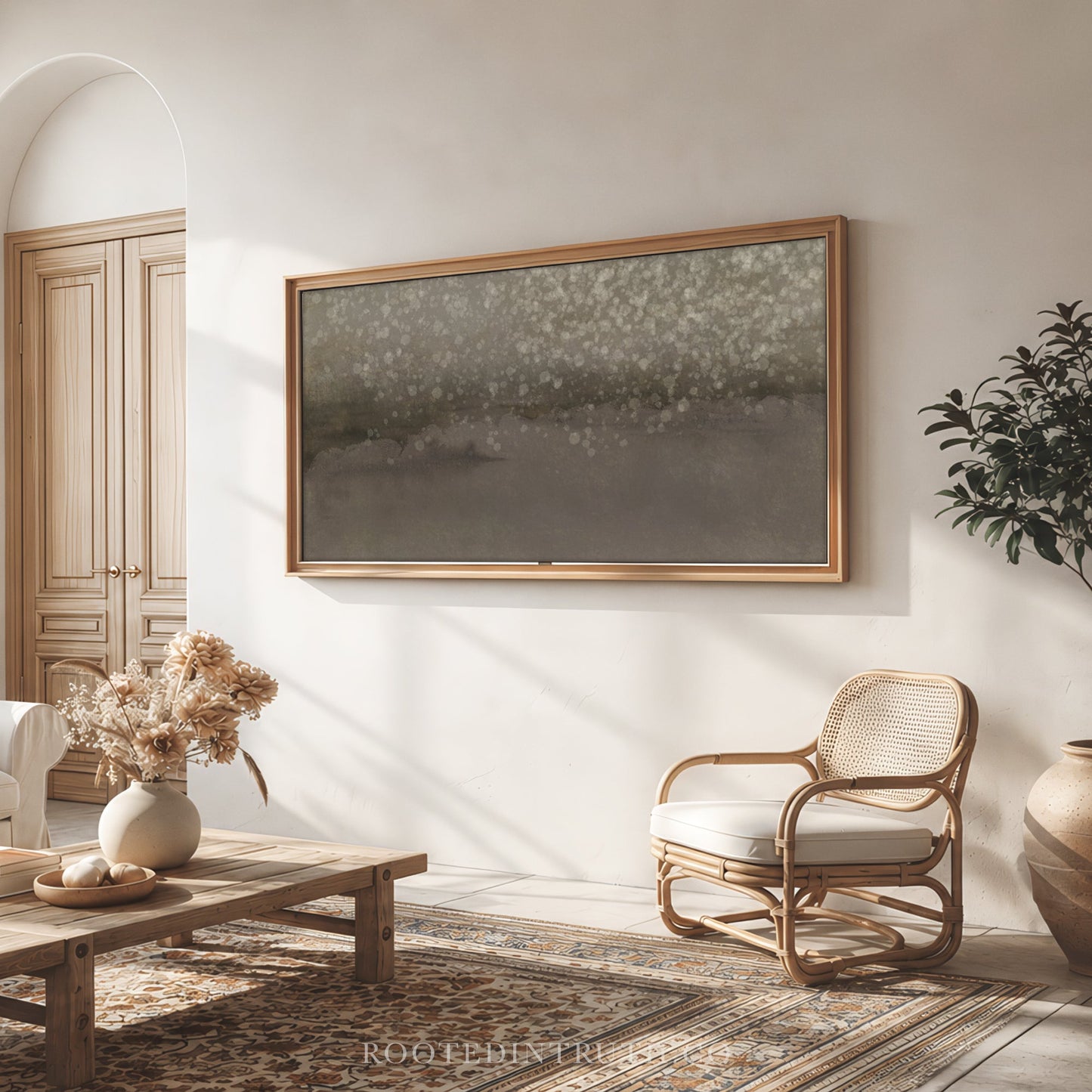 a cozy living room with a large framed artwork hanging on the wall, a wooden coffee table, a woven chair, and a potted plant.
