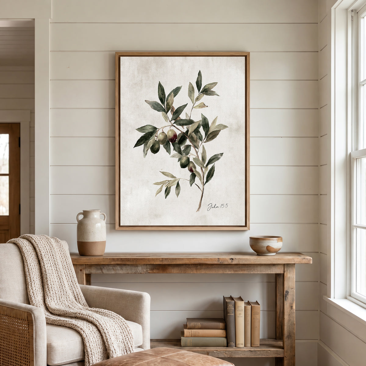 a cozy living room with a wooden console table, a beige armchair, and a framed painting of an olive tree hanging on the wall.