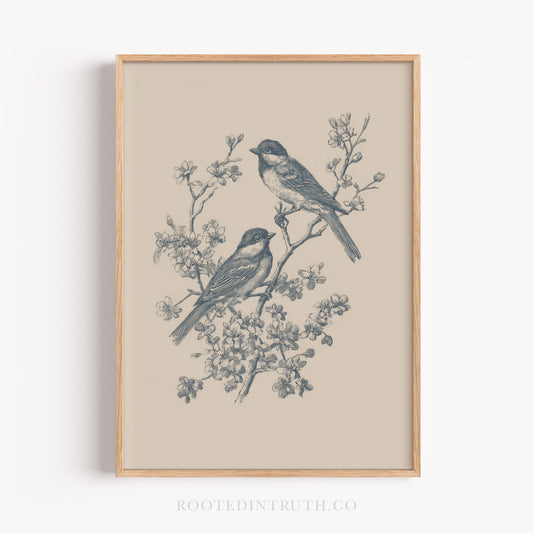 A framed illustration of two birds perched on a branch with flowers.