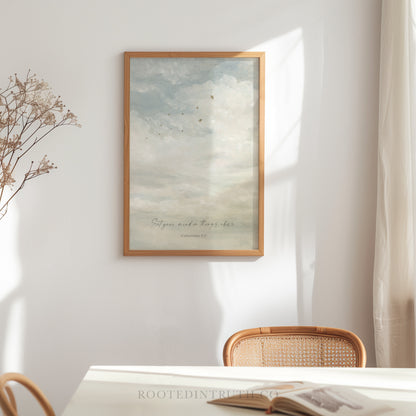 a serene indoor setting with a white wall, a wooden chair, and a framed print of a cloudy sky with birds. The print is hanging above a table with a book on it.